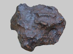 A brown-gray meteorite that's roughly circular with textured ridges