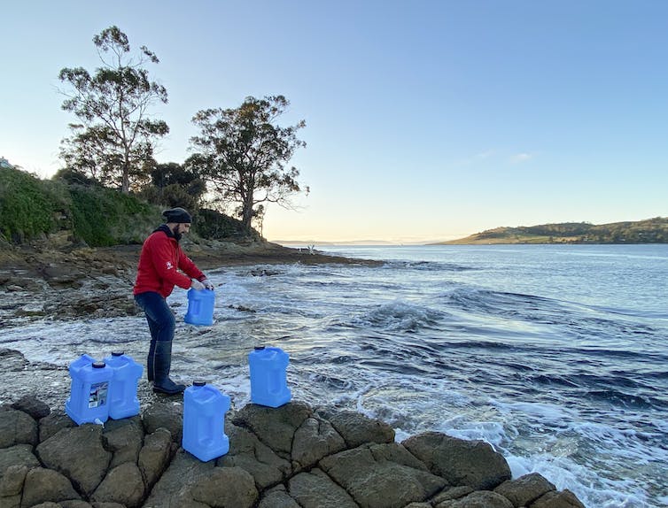 man collecting DNA samples in buckets of river water